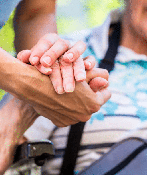 caretaker holding hand of older person in the wheelchar