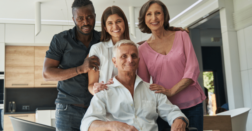 elderly person in wheelchair with smiling people around